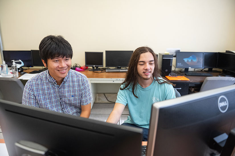Faculty and student sitting at computer going over classwork
