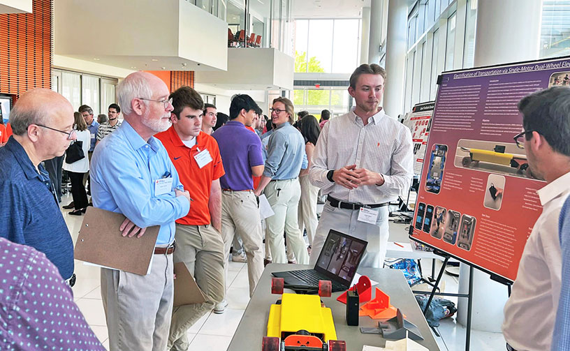 Student presenting project with group of judges onlooking