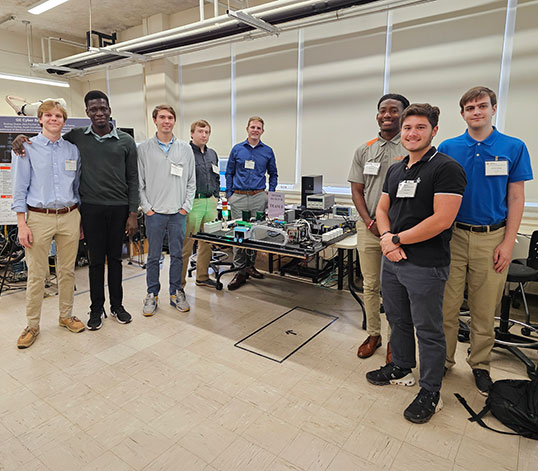 Group posing with their design in the background