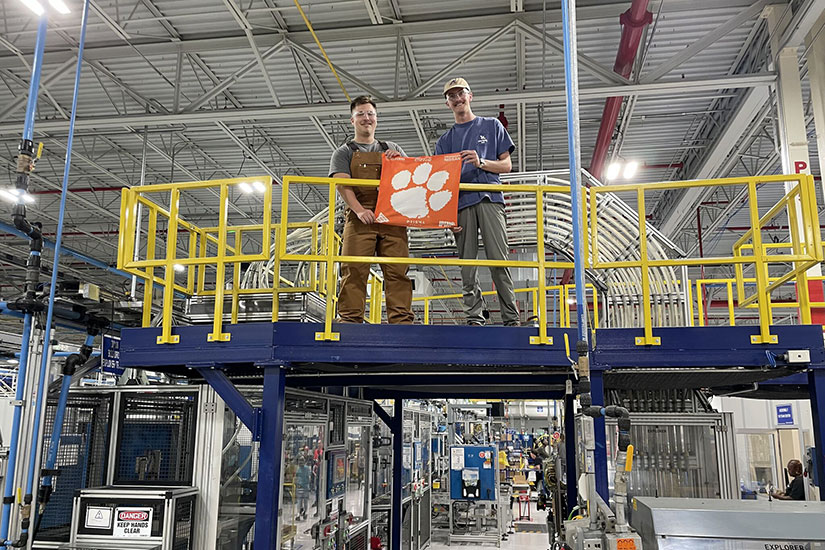 Students holding tiger rag while on scaffolding at work