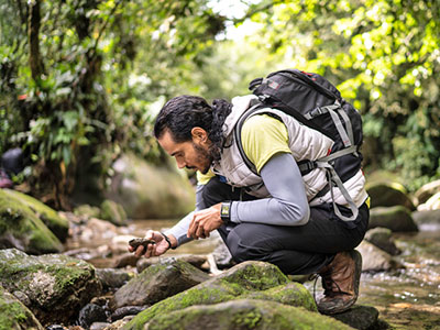 Male engineer looking at rocks along stream.