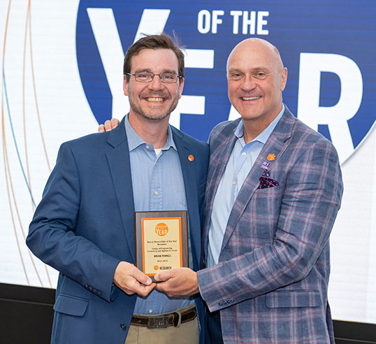 Faculty member with University President, accepting award.