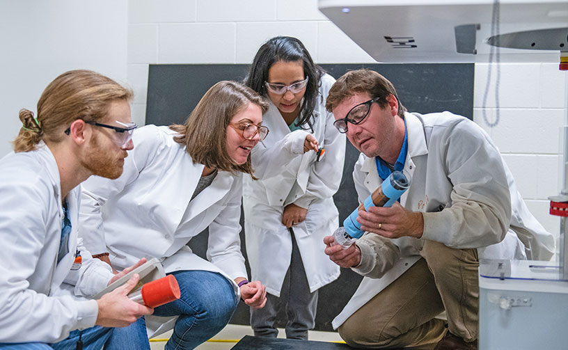 Powell with students examining tube.