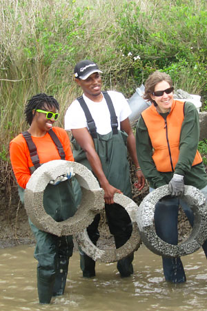 Three students in water, decked out in waterproof gear.