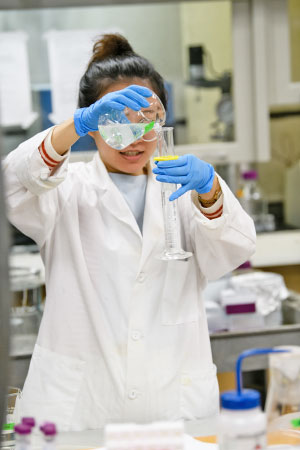 Female student in lab measuring in tube.