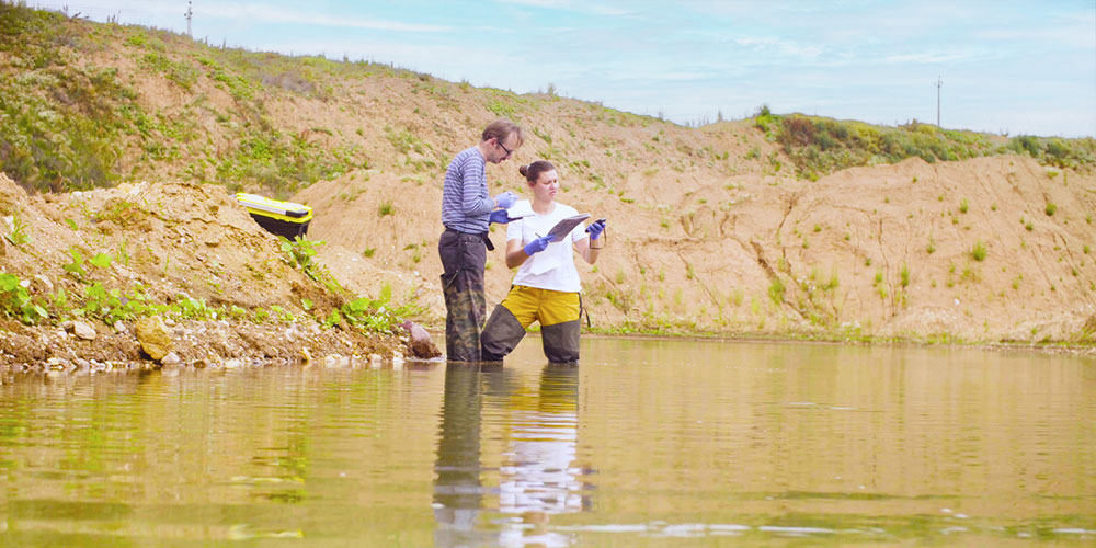 Male and female in pond performing monitoring practices.