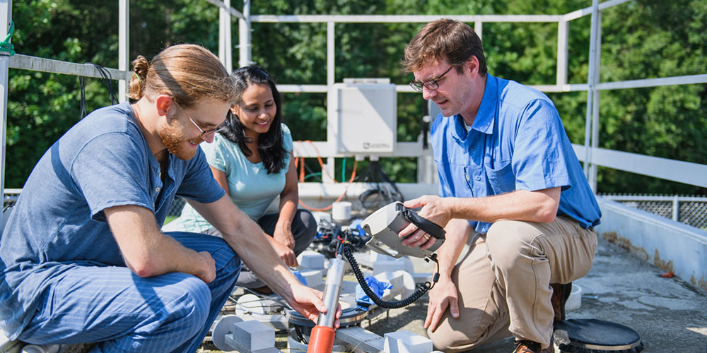 Faculty and students working outside on machine.