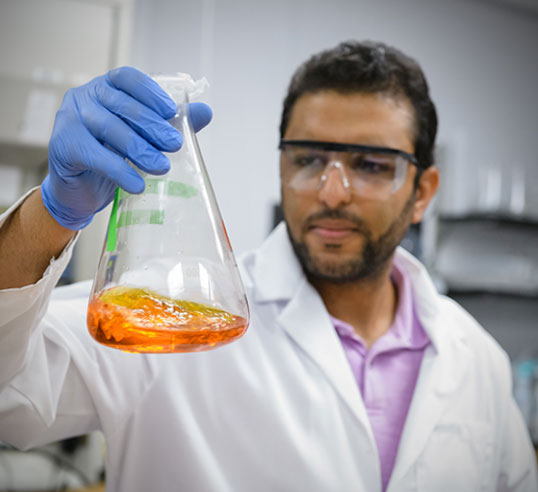 Male student holding up beaker in lab.