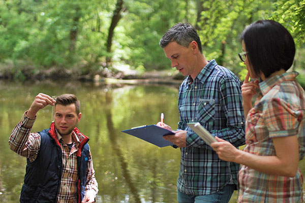 Three individuals looking at water samples and taking notes.