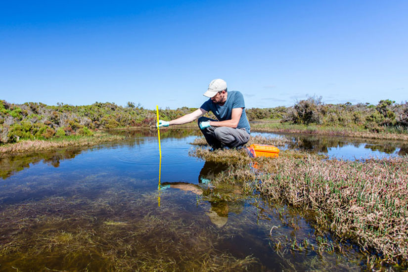 Man taking measuring water depth in river pool.