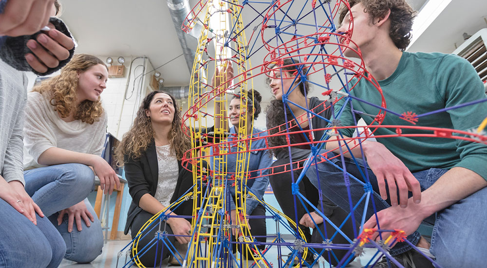 Group of students and teacher looking at engineered structure