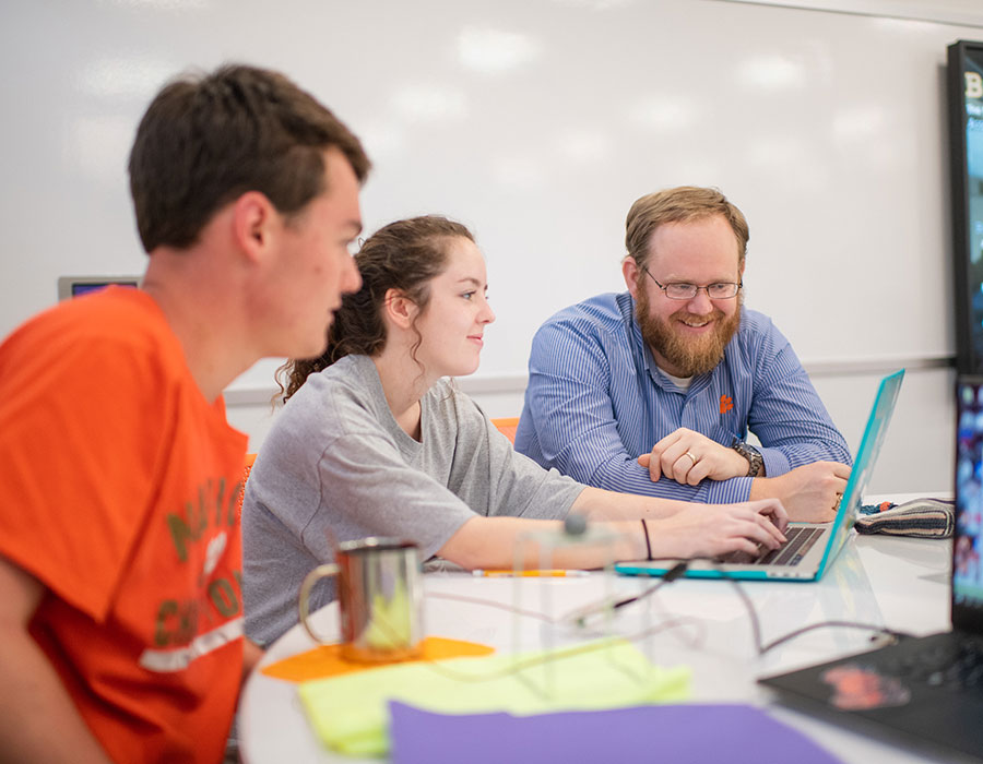 Faculty member helping 2 students in engineering class.