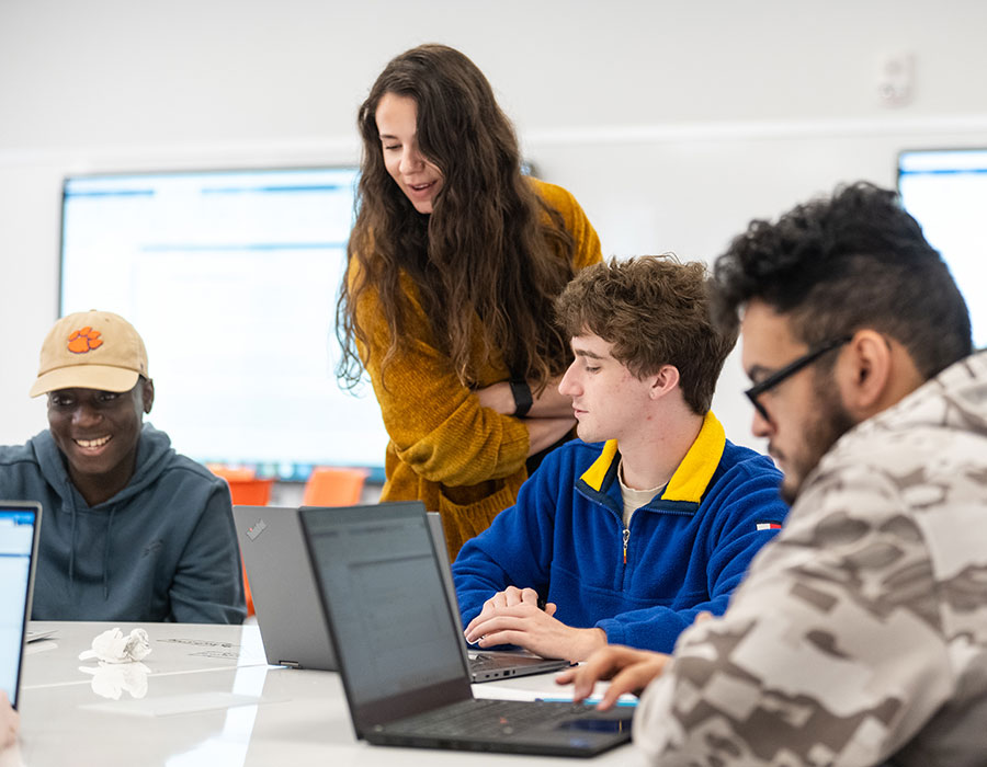 Faculty member helping three students in Engineering 1410.