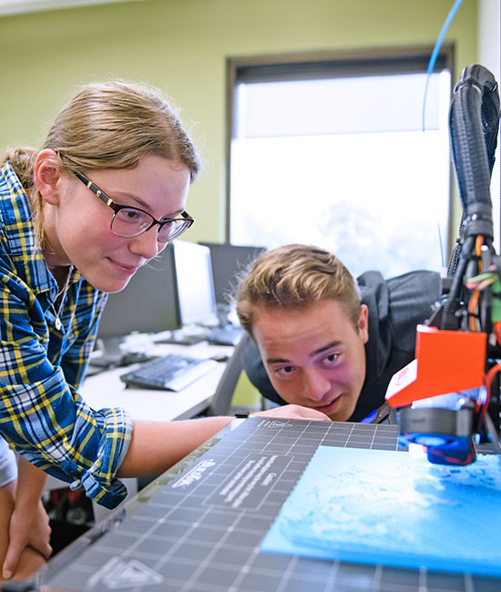 Two students using equipment to make 3d object