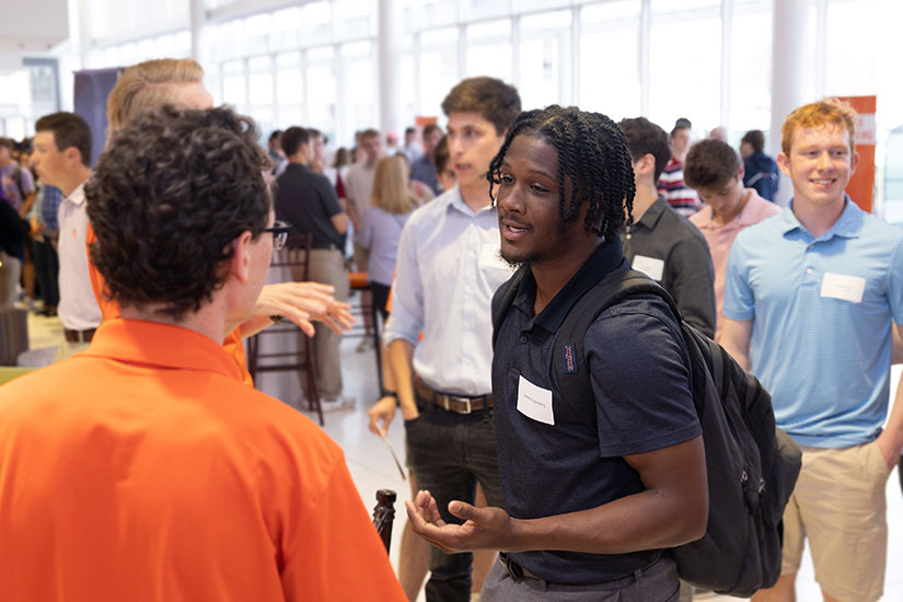 A group of students engaged in conversation at a networking event in Watts.