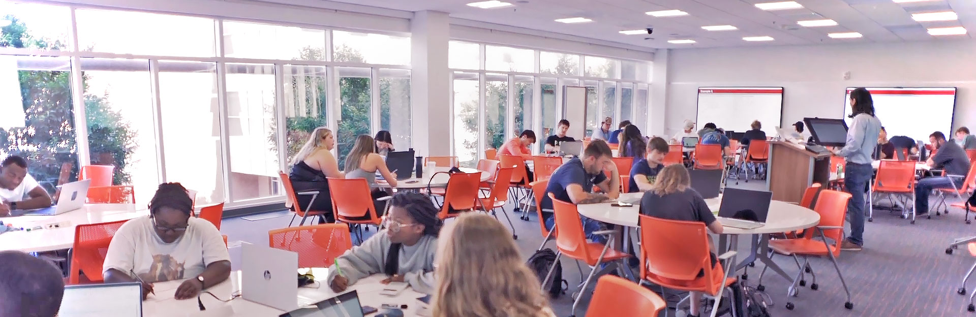 Students in bright classroom working on assignment with teacher in background