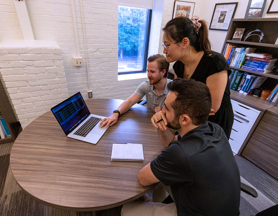 Group gathered around laptop to work on research.