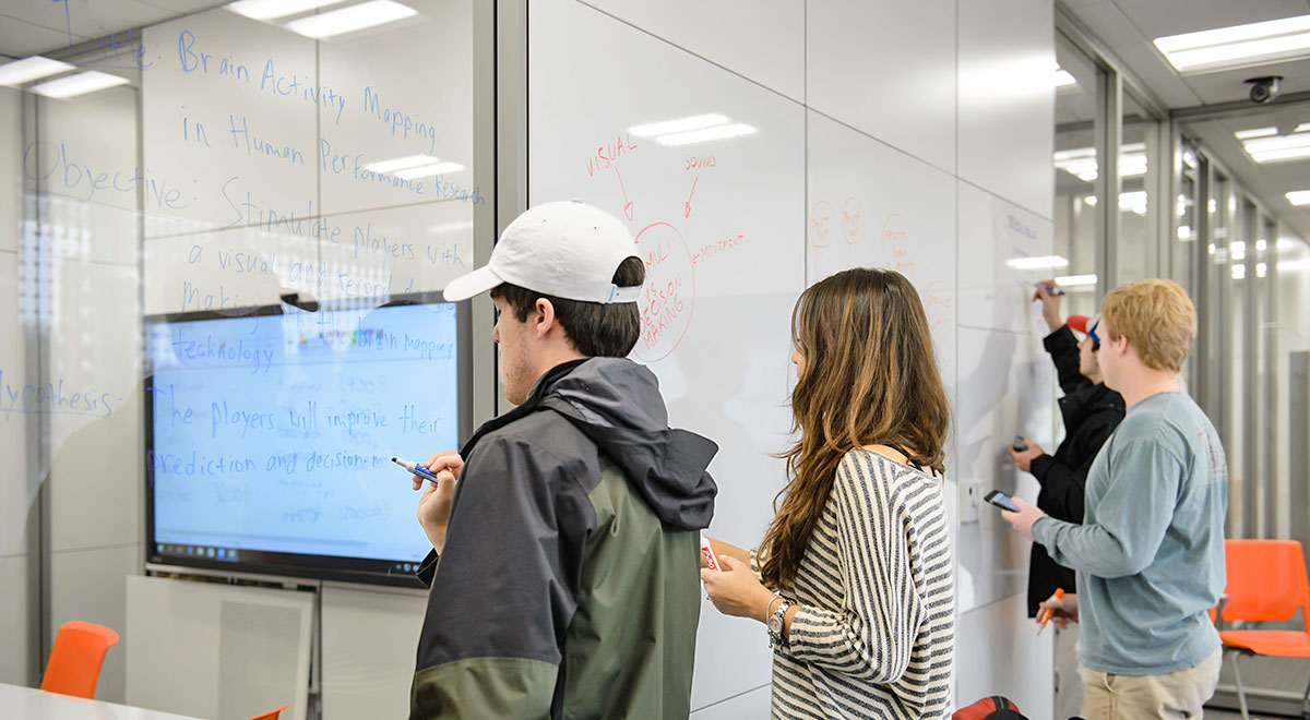 IE Students writing on board during class research project.