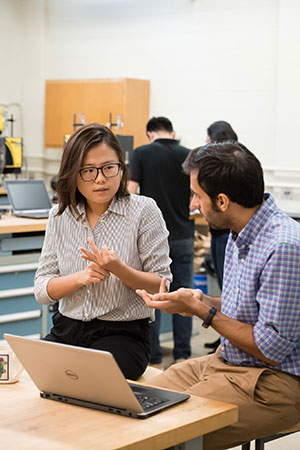 Man and woman discussing work over laptop in the lab.