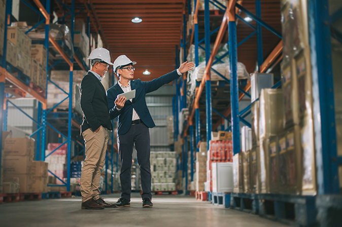 Two employees discussing logistics in a warehouse.