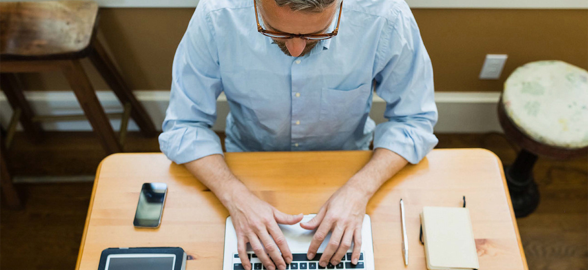 Man working on his laptop while sitting at table.