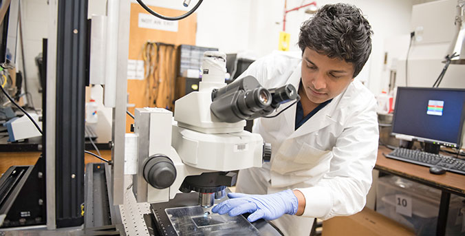 Student in lab over scope.