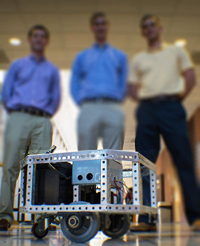 Students standing over machine they built.