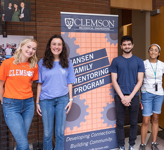 Students stand in front of Jansen Family Mentoring Program banner.