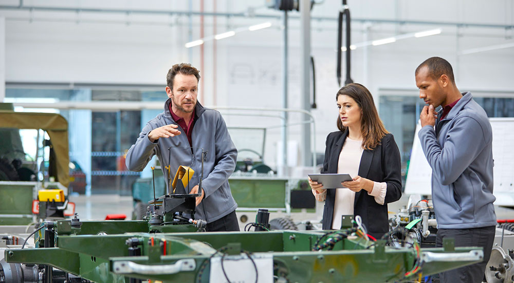 Three people looking at equipment in plant.