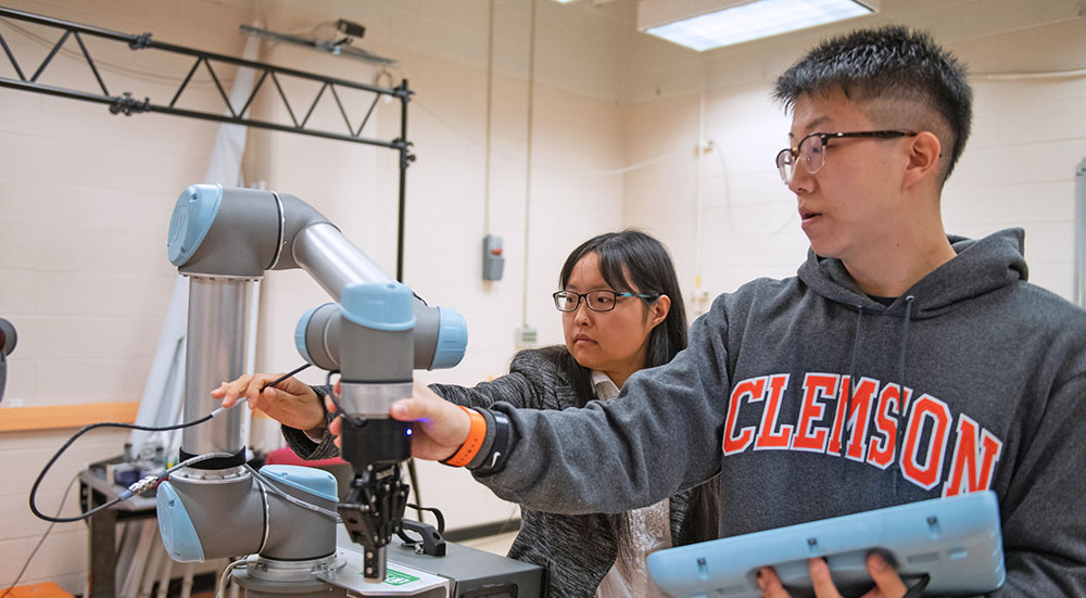 Wang and student working on robotic arm.