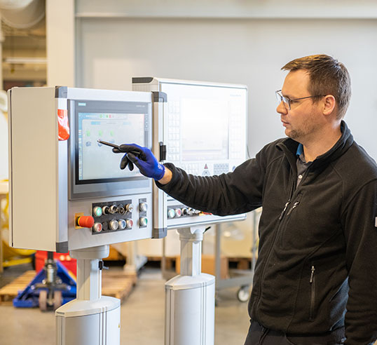 Employee working on machine with large screen.