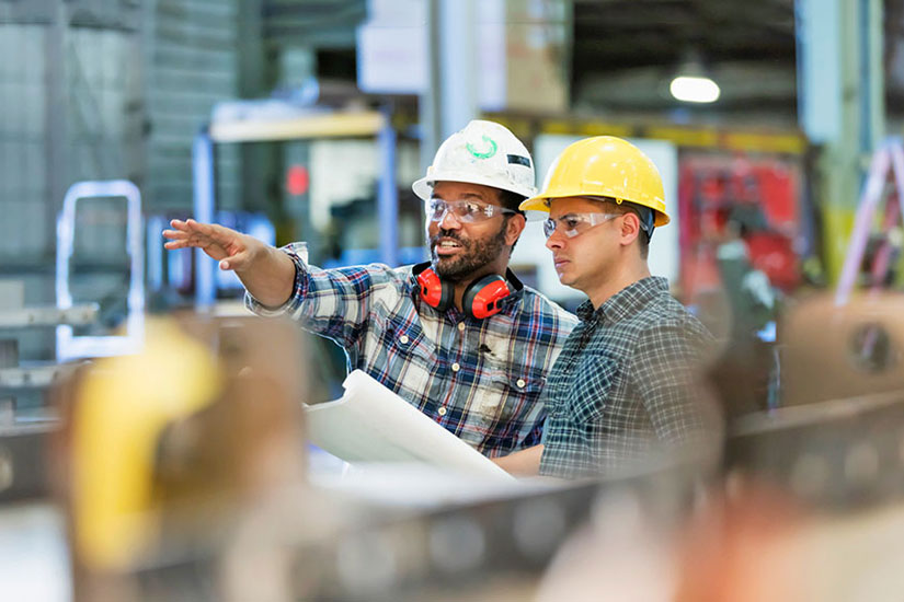 Employees in hard hat on plant floor.