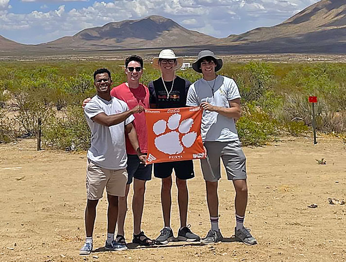 Group from Rocket Engineering Club at competition out west with orange tiger rag flag. 