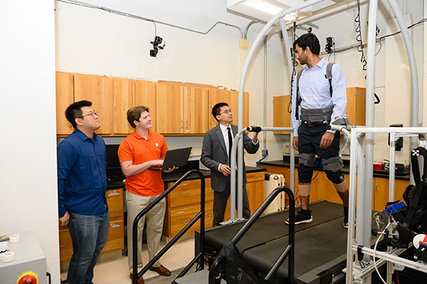 Faculty and graduate students working together as they test robotics equipment on a student.