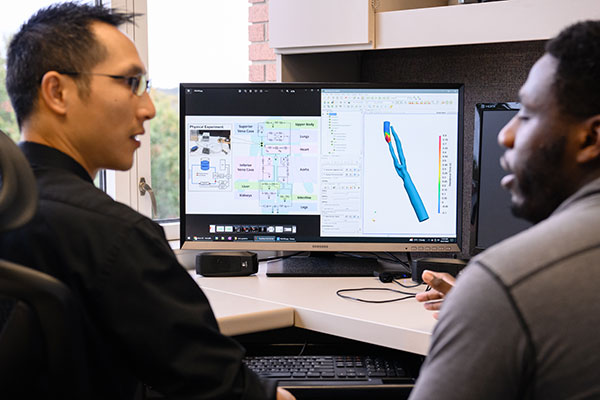 Student sitting at desk with Kung as they review vascular imagery on the screen.
