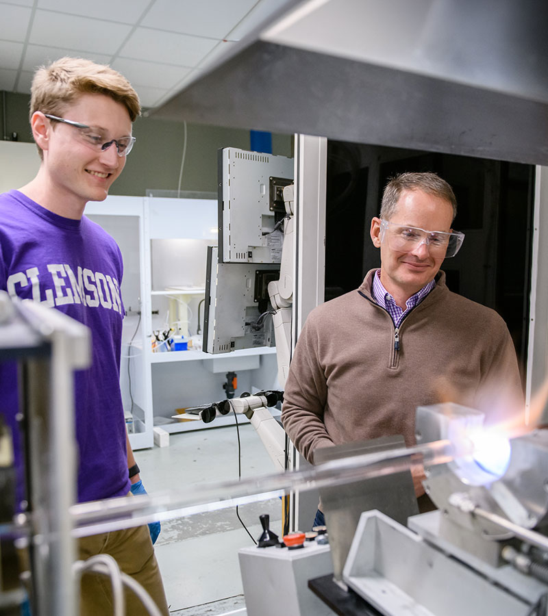 Graduate student in AMRL lab with Ballato and laser equipment.