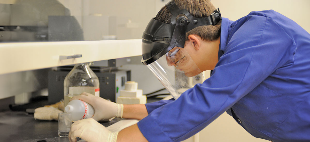 Student carefully pouring substance into beaker in lab