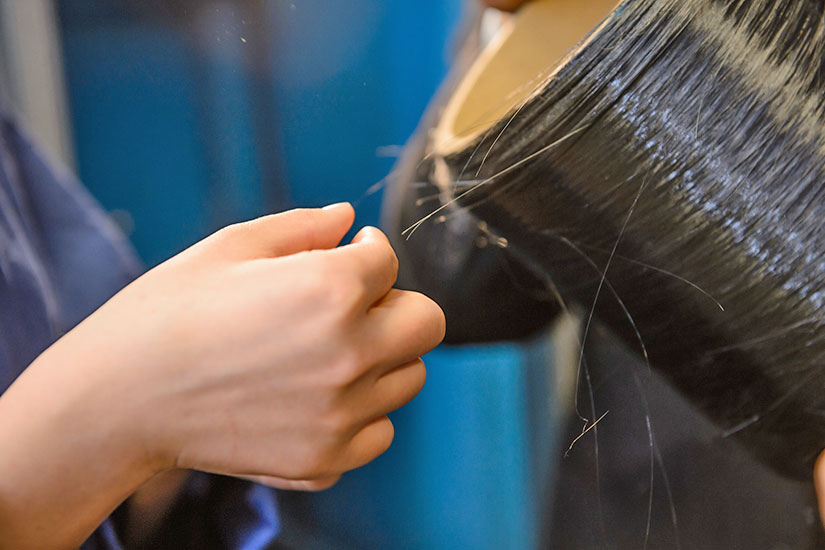 Up close of person touching fibers from spool