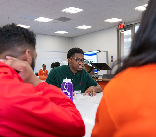 Student smiling while at a table talking to others