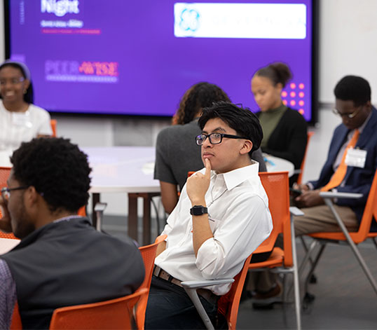 Group of students at event with one pondering speaker's words