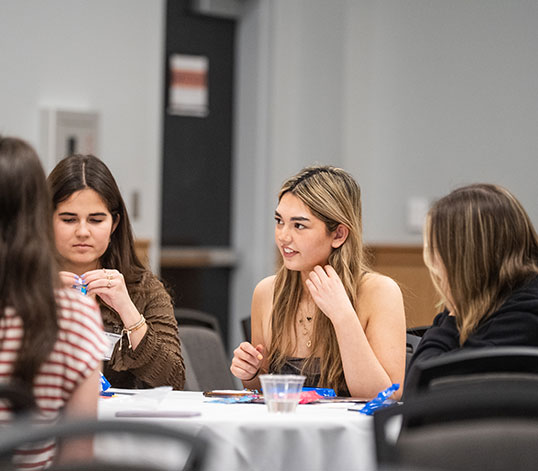 Close up of female student eating with several others at table