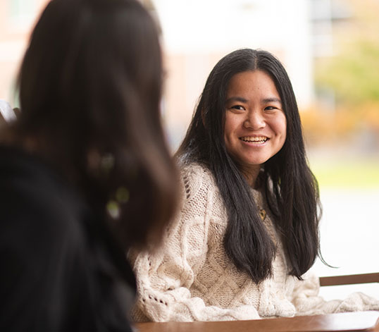 Two students sitting in rocking chairs talking