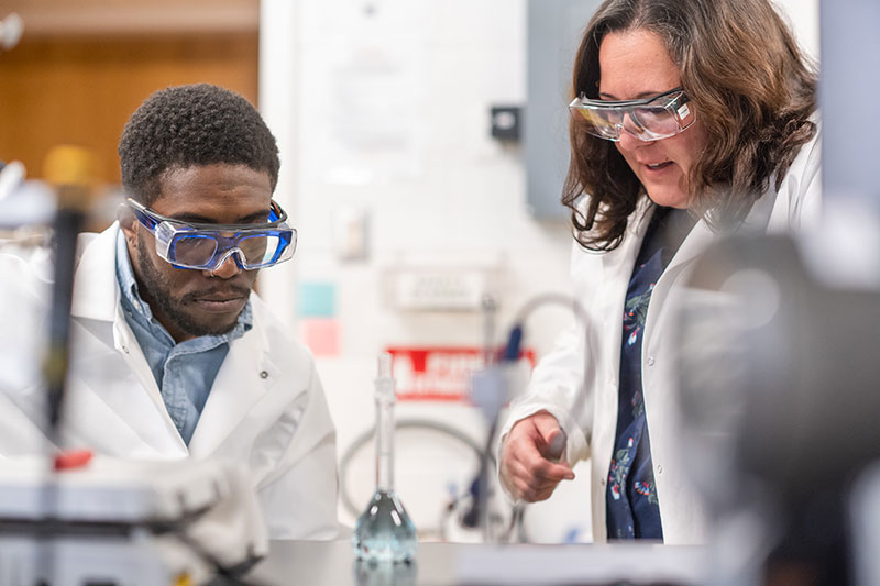  Student and faculty member appear closely at the research they are working on in the lab.