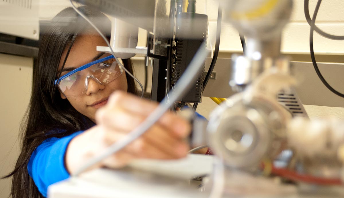 Female in safety glasses in lab with scope