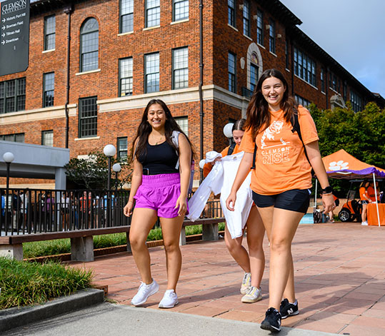 Smiling students on campus in front of Riggs Hall