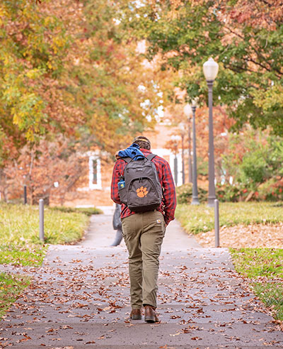 Student walking with Clemson backpack on
