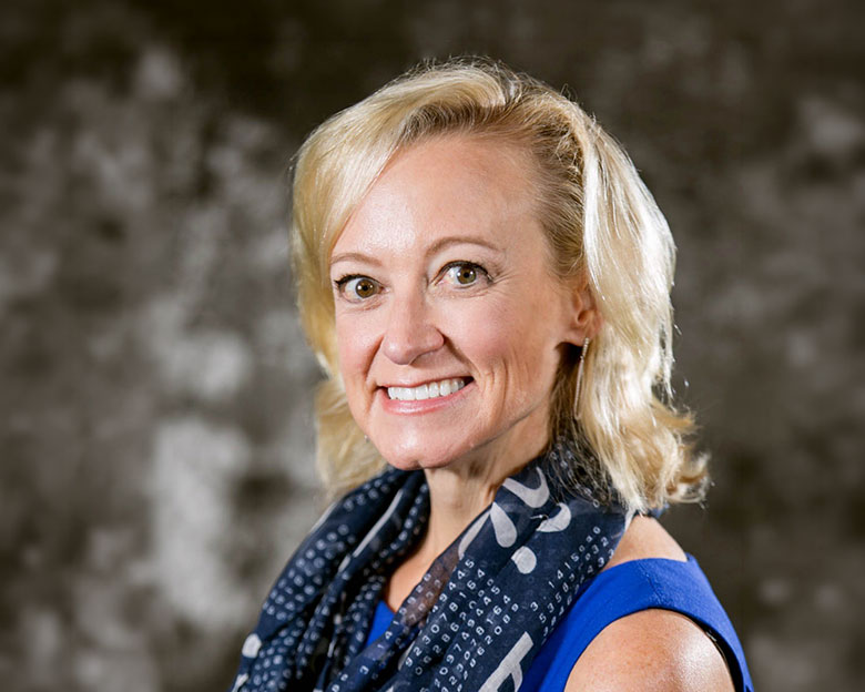 Farnoosh Brock, author, sitting in her living room, smiling at the camera.