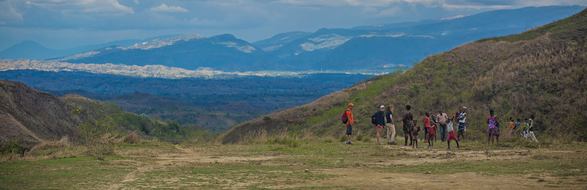 Student hiking in Haiti with children form the area.