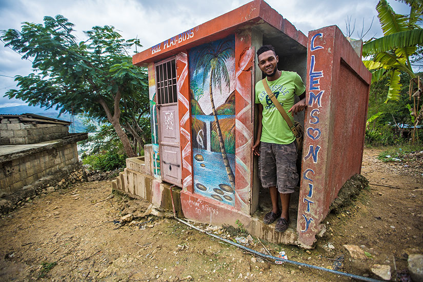 Young man in concrete building in Haiti with "Clemson City" on the side
