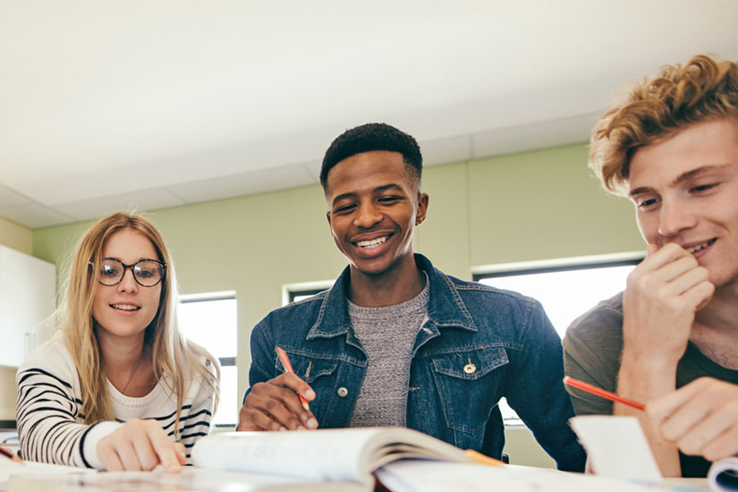 Three students at table with papers and books